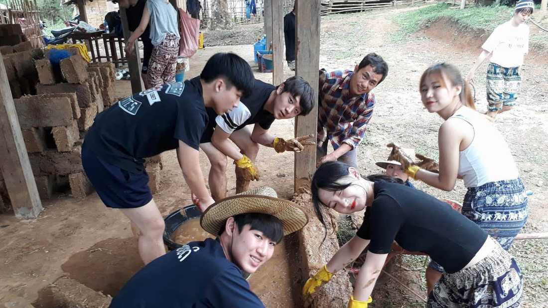 Students building a wall using Adobe bricks